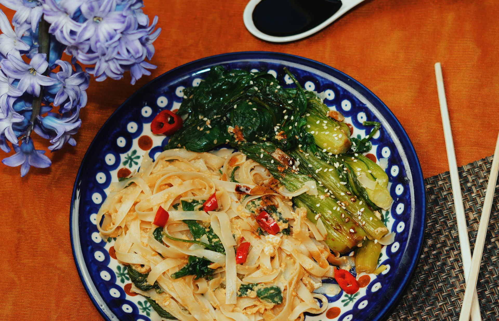 a plate of noodles and vegetables with chopsticks